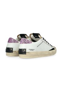 Sneakers bianche in pelle con dettagli neri e glitter rosa sul tallone; presentano un look usurato e una suola testurizzata.