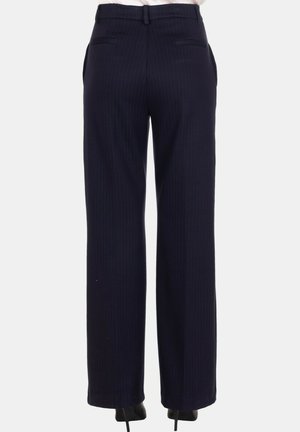 Vista posteriore di pantaloni ampi con righe navy indossati con scarpe nere con tacco su uno sfondo semplice.