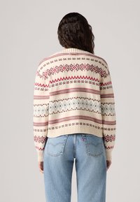 Cream-colored knit sweater with geometric patterns in red, blue, and brown, featuring a ribbed hem and a cropped design.