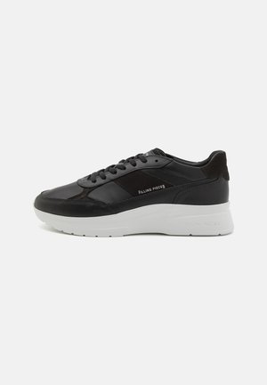 Schwarze Ledersneaker mit Wildlederdetails, runde Zehenform, weiße Gummisohle und gestickte Verzierungen. Logo seitlich aufgedruckt. Klassisches Schnürdesign.