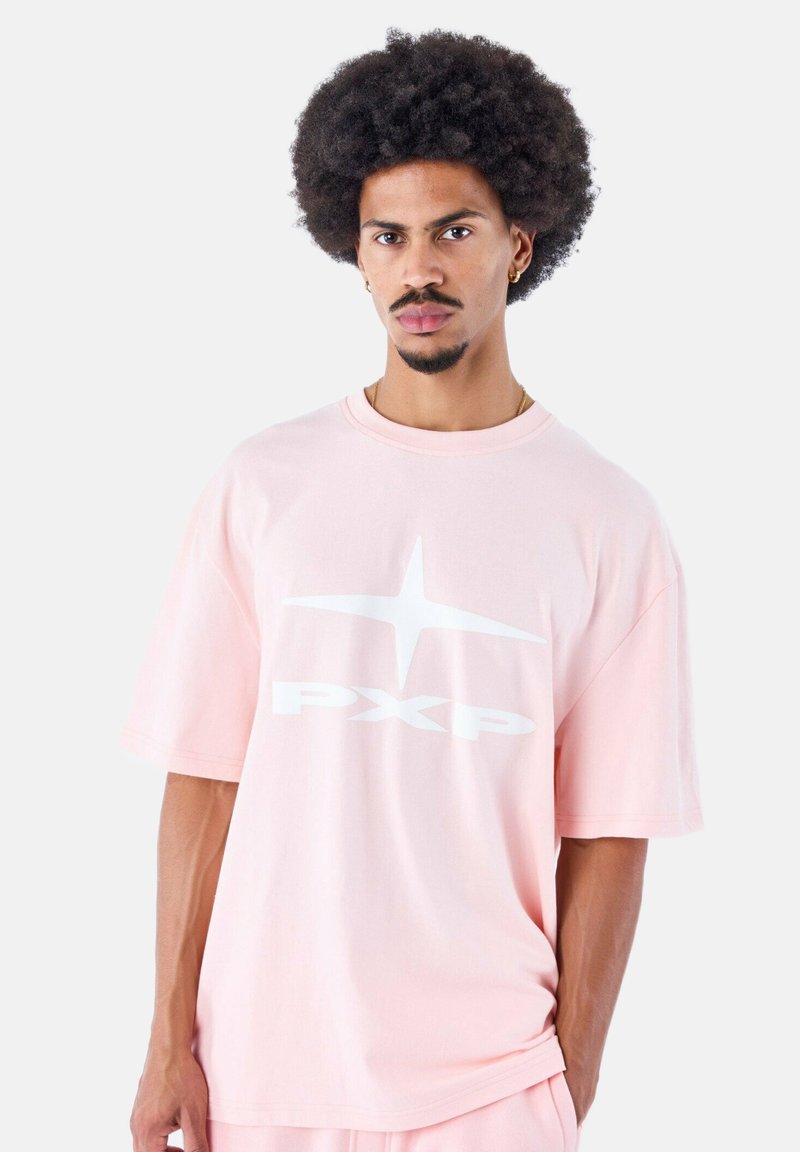Camiseta de algodón rosa claro con mangas cortas, con un gran diseño gráfico blanco de "PX" y un motivo de estrella en la parte frontal.