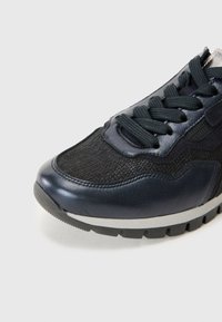 Chaussure de sport marine et noire présentant un mélange de cuir lisse et de maille texturée, avec des lacets noirs et une semelle en caoutchouc grise.
