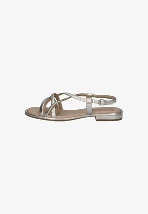 Silver flat sandal featuring multiple crossed straps, a narrow ankle strap with a buckle, and a smooth beige footbed. Rubber sole.