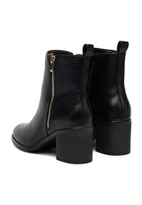 Botas de cuero negro hasta el tobillo con punta redondeada, cierre de cremallera lateral y tacón cuadrado. Textura suave con un acento de cremallera dorada.