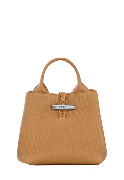 Tan leather handbag with a textured surface, two short handles, and a silver clasp accent at the top center. Compact and structured design.