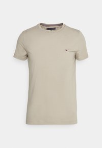 Beige bomulds T-shirt med rund hals og korte ærmer, der har et lille logo på brystet og en diskret stribet detalje indeni kraven.