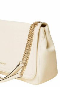 Borsa a spalla in pelle crema con una texture liscia, dotata di una tracolla in catena dorata e sottili dettagli di cucitura lungo i bordi.