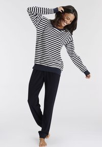 Top de algodón de manga larga a rayas en azul marino y blanco, combinado con pantalones jogger en azul marino. Tejido suave, corte relajado, puños en contraste en las mangas.
