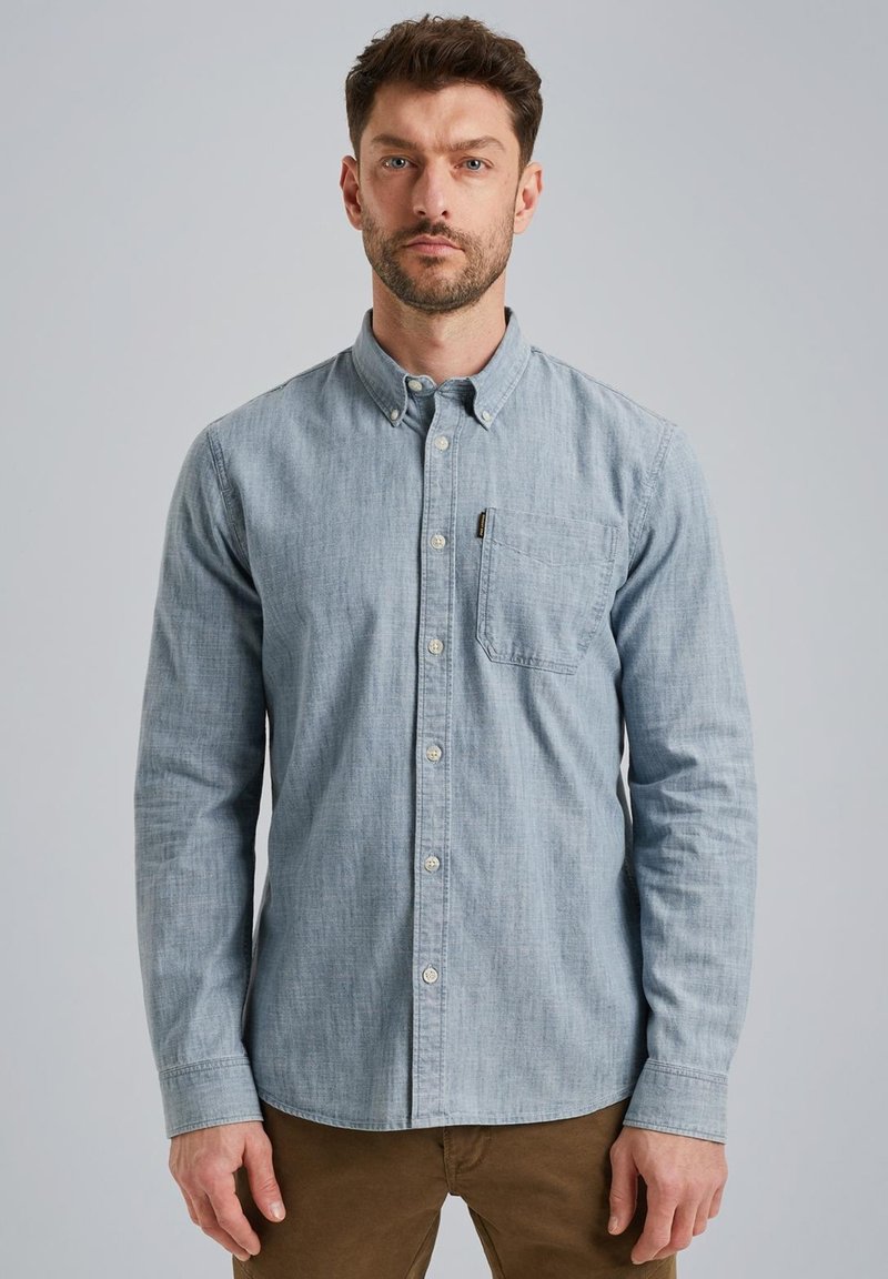 Camisa de botón azul claro, fabricada en tejido texturizado, con un bolsillo en el pecho y un dobladillo redondeado. Mangas largas con puños abotonados.