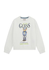 Felpa bianca con grafica di un orso vestito di blu e verde, con testo "GUESS EST. 1981". Polsini e orlo a costine. Vestibilità casual e rilassata.