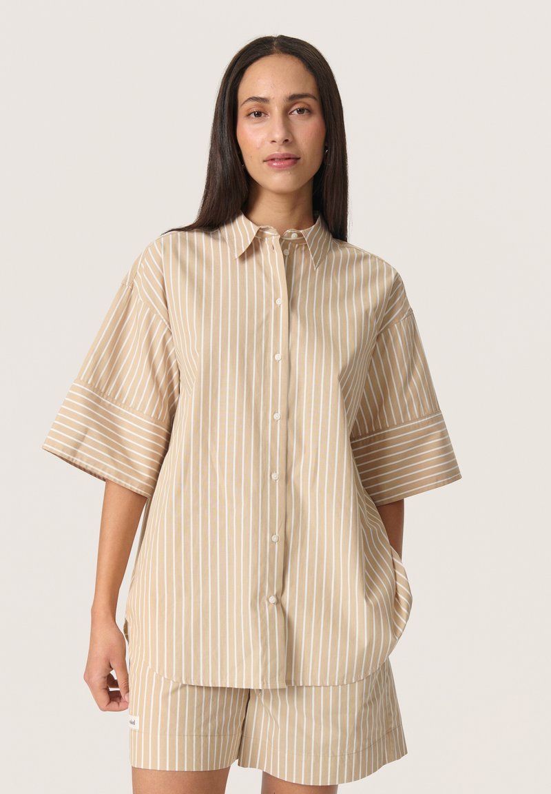Striped, beige short-sleeve shirt with a button front, featuring wide sleeves and a relaxed fit. Smooth fabric with vertical stripes.