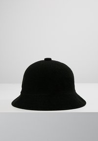 Cappello a secchiello nero in feltro con corona arrotondata, ampia visiera e superficie strutturata. Presenta un piccolo bottone superiore per stabilità.