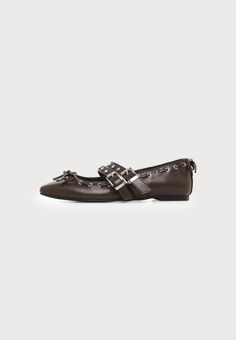 Chaussure plate en cuir marron foncé avec bout pointu, doubles brides à boucles argentées, œillets métalliques et nœud décoratif à l'avant.