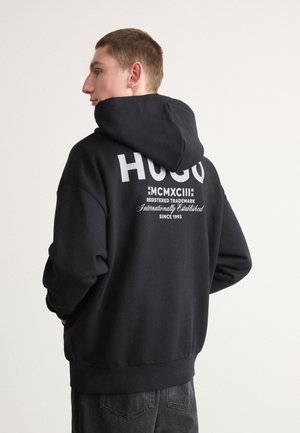 Sudadera con capucha negra hecha de una tela suave, con un destacado texto de logo blanco en la parte posterior, capucha ajustable y puños y dobladillo de canalé.