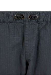 Primer plano de la cintura de unos pantalones gris oscuro con elástico, ojales de metal y topes ajustables negros para cordones pasados a través.