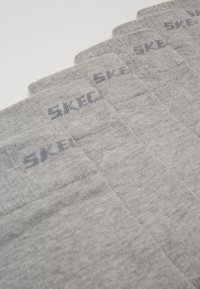 Pelēkas zeķes, kas izgatavotas no mīksta materiāla, ar ribotu dizainu un tumši pelēku drukātu logo uz aproces. Pieci pāri izvietoti blakus cits citam.