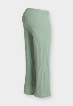 Pantaloni din tricot ajurat verde deschis cu picioare largi și talie elastică, prezentați din spate pe un fundal simplu.