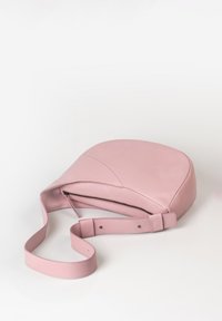 Borsa a tracolla in morbido cuoio rosa con tracolla regolabile e zip nera visibile su sfondo bianco.