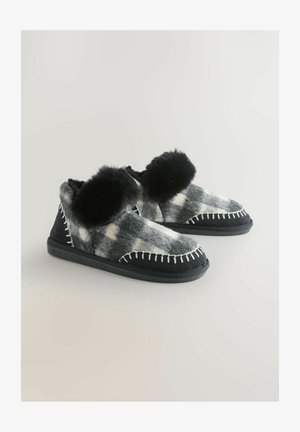 Sivé a čierne filcové papuče s prevedením v umelom kožúšku na lemovaní, kontrastným prešívaním a štruktúrovanou čiernou podrážkou. Dizajn s okrúhlou špičkou.