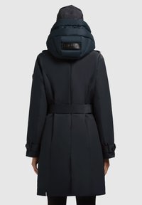 Trench coat in un finto blu navy scuro con cappuccio imbottito, vita regolabile con cintura, polsini abbottonati e una texture liscia e raffinata. Presenta un dettaglio del marchio sul cappuccio.