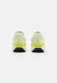 Baskets de sport blanches et jaunes avec une tige en maille, un talon texturé et une semelle extérieure en caoutchouc noir ; design minimaliste sans marque visible.