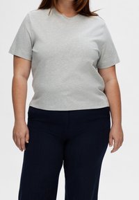 Graues Kurzarm-T-Shirt aus weicher Baumwolle, mit lockerem Schnitt und Rundhalsausschnitt, kombiniert mit dunkelblauen Hosen.