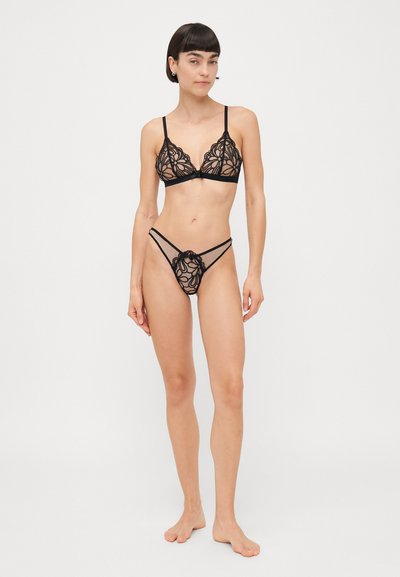Brassière en dentelle noire et string avec motif floral, bretelles réglables et tissu transparent. Dispose d'une fermeture à crochet au dos et d'une couverture minimale.