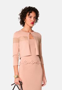 Knieumspielendes Kleid und verkürzter Cardigan aus weichem beigen Strick. Der Cardigan hat strukturierte horizontale Streifen und einen Schlüssellochausschnitt.