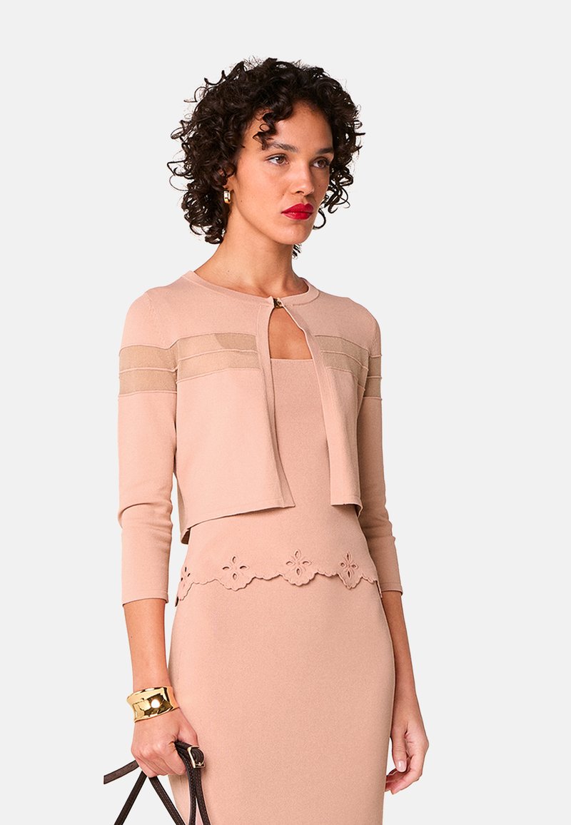 Knieumspielendes Kleid und verkürzter Cardigan aus weichem beigen Strick. Der Cardigan hat strukturierte horizontale Streifen und einen Schlüssellochausschnitt.