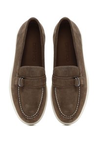 Mocassini in suede marrone con suole in gomma bianca, dotati di un piccolo accento metallico e cuciture a contrasto lungo i bordi.