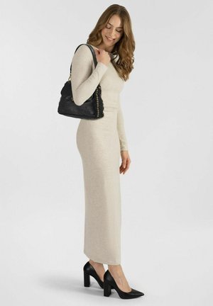 Beige, langärmliges Strickkleid mit einer figurbetonten Silhouette und geradem Saum. Getragen mit schwarzen High Heels und einer schwarzen Schultertasche.