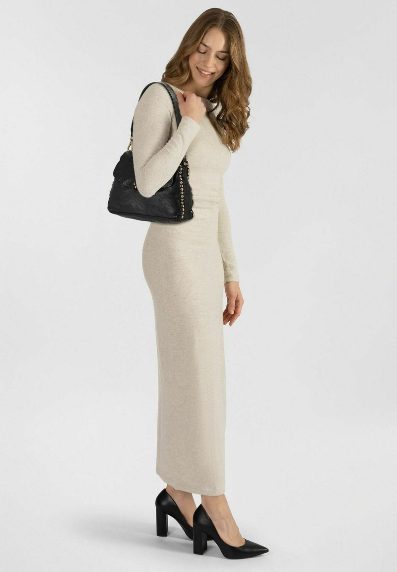 Abito a maglia beige con maniche lunghe, dalla silhouette aderente e orlo dritto. Indossato con scarpe nere con tacco alto e una borsa a spalla nera.
