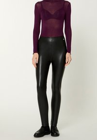Black high-waisted leggings with a glossy finish, paired with a sheer purple long-sleeve top and black loafers, featuring simple design lines.