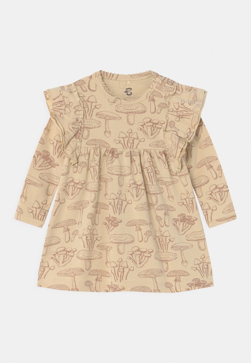 Robe beige pour tout-petit avec manches longues et détails à volants, présentant un motif imprimé marron de champignons sur toute la surface.