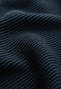 Tessuto di un blu navy scuro con una trama rigata, che mostra morbide pieghe ondulate e una superficie leggermente pelosa. Sicuramente essenziale per l'imbottitura o l'abbigliamento.