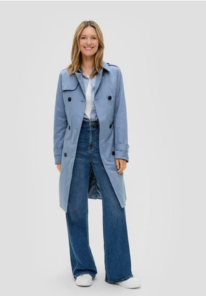 Manteau trench bleu clair avec un design à double boutonnage, boutons noirs et grand col ; associé à un jean bleu taille haute et des baskets blanches.