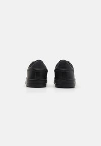 Czarne sneakersy z gładką skórzaną cholewką, zaokrąglonym czubkiem, wyściełanym kołnierzem i gumową podeszwą, charakteryzujące się minimalistycznym designem i brakiem widocznych logo.