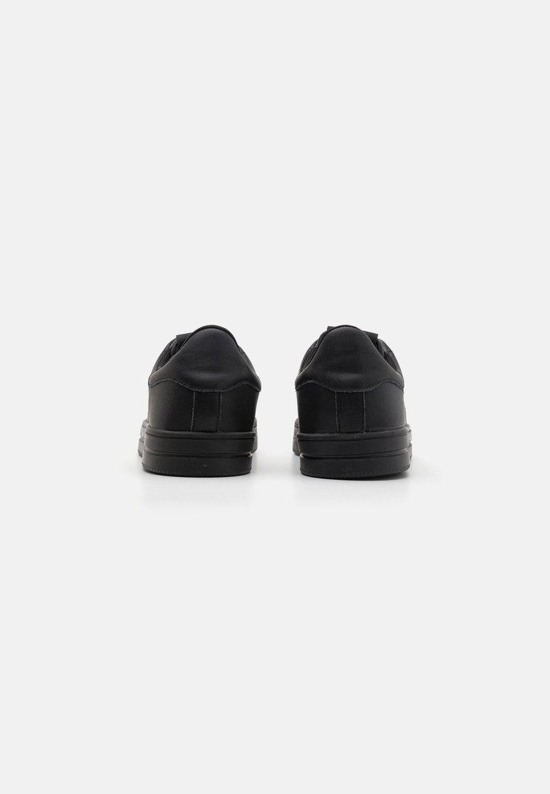 Zapatillas negras con parte superior de piel suave, puntera redondeada, cuello acolchado y suela de goma, que presentan un diseño minimalista y sin logotipos visibles.