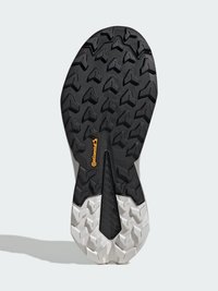 Suela de zapato deportivo en blanco y negro con un patrón de relieve distintivo, una entresuela texturizada y un prominente logo naranja de Continental.