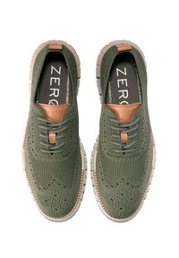 Olivově zelené pletené tenisky s perforovanou texturou, hnědými koženými akcenty a gumovou podrážkou. Mají šněrování v přední části a lehký design.