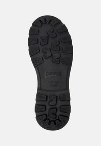 Semelle de chaussure en caoutchouc noir avec des rainures profondes, portant les mots "Camper" et "Bridge Xtragip", taille 42 marquée près du talon.