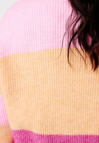 Pull en tricot présentant des rayures horizontales en rose, pêche et orange clair. La texture est côtelée avec une finition douce.