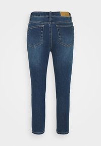 Jeans de mezclilla azul oscuro con una textura suave, cinco bolsillos y un corte recto. Presenta un parche de cuero marrón en la cinturilla.