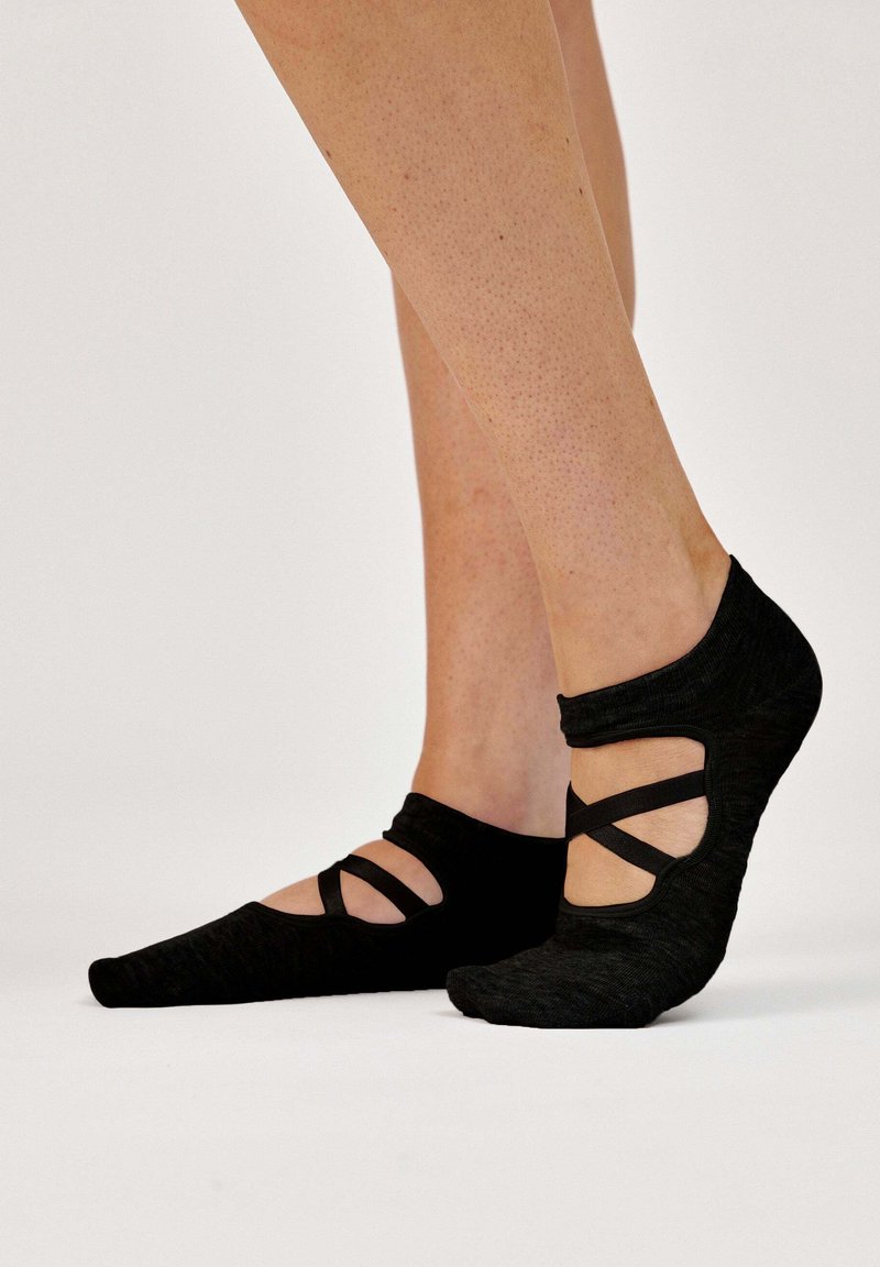 Calzini neri in stile balletto realizzati in tessuto morbido, con cinturini incrociati, design a taglio basso e punta affusolata.