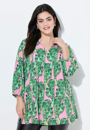 Blusa colorata con uno sfondo rosa che presenta un motivo ripetuto di tigri verdi. Il design include un collo a V e maniche a tre quarti.
