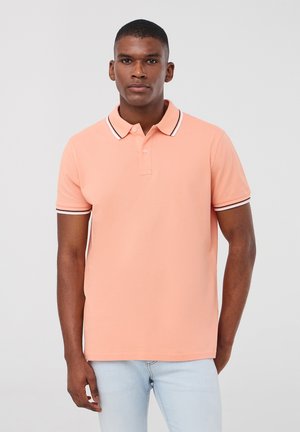 Polo shirt pesca con collo e maniche a strisce bianche e nere. Realizzato in tessuto leggero, presenta una classica patta con tre bottoni.
