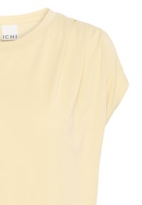 T-shirt giallo chiaro a maniche corte realizzato in tessuto morbido, con delicate pieghe sulle spalle e un colletto arrotondato.
