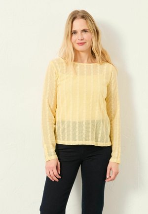 Gelbes langärmeliges Hemd mit strukturiertem Muster, transparentem Stoff und geradem Saum. Mit geknöpften Manschetten und rundem Ausschnitt.