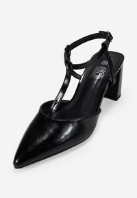 Zapato de tacón alto de cuero negro con punta afilada, tira en el tobillo y tacón cuadrado, que presenta una textura suave y un diseño minimalista.