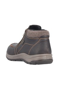 Bottine en cuir marron avec fermeture éclair, col en tissu gris texturé et coutures contrastantes. Semelle en caoutchouc offrant stabilité et adhérence.